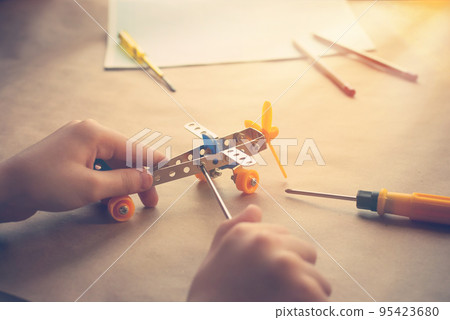 Children hands with Toy iron plane. Metal constructor with screwdrivers. Dream, play and create Children hands with Toy iron plane. Metal constructor with screwdrivers. Dream, play and create 95423680