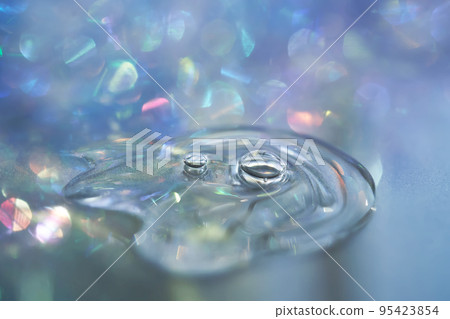 A drop of serum in tinsel in a Christmas theme in purple shades in dark tones. A drop of serum in tinsel in a Christmas theme in purple shades in dark tones. 95423854