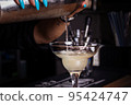 Girl bartender pours cocktail into glass. Close-up. 95424747