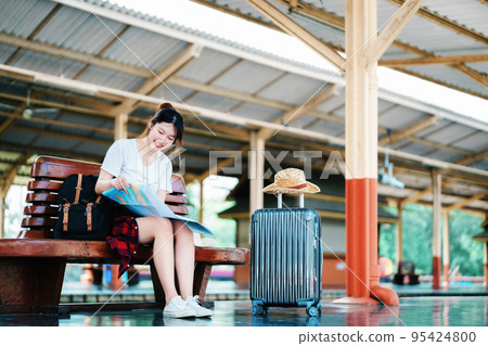 summer, relax, vacation, travel, portrait of a cute Asian girl looking at a map to plan a trip while waiting at the train station summer, relax, vacation, travel, portrait of a cute Asian girl looking at a map to plan a trip while waiting at the train station 95424800