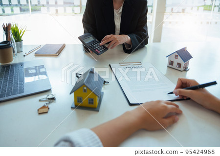 Guarantee, mortgage, contract, contract, signed, real estate agent or bank officer holding a calculator, submits a bid with a customer to buy a home before signing to make a deal. 95424968