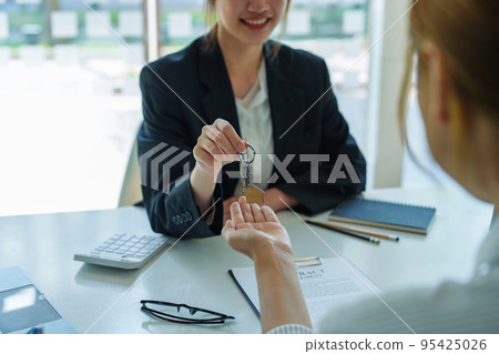 Accountant, businessman, real estate agent, Asian business woman handing keys to customers along with house after customers to sign. Accountant, businessman, real estate agent, Asian business woman handing keys to customers along with house after customers to sign. 95425026