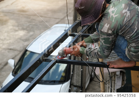 The contractor is using an electric grinder to decorate the steel welding point 95425358