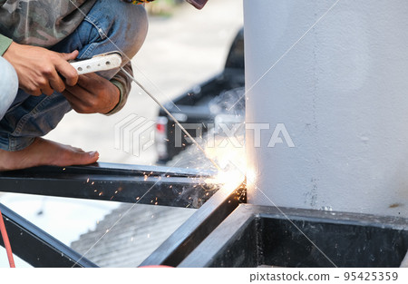The welder is welding the steel structure to add to the house The welder is welding the steel structure to add to the house 95425359