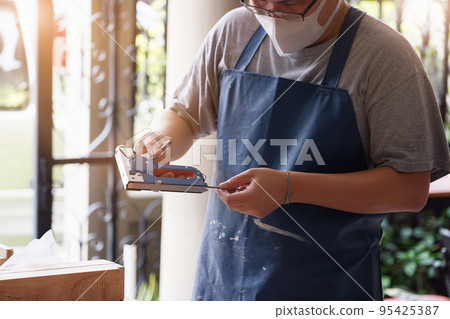 Entrepreneur Woodwork holding a Tacker to assemble the wood pieces as the customer ordered. 95425387