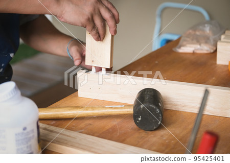 Woodworking operators are using glue to put together the wood parts to assemble and build a wooden table for their customers. Woodworking operators are using glue to put together the wood parts to assemble and build a wooden table for their customers. 95425401