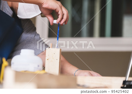Woodworking operators are using glue to put together the wood parts to assemble and build a wooden table for their customers. Woodworking operators are using glue to put together the wood parts to assemble and build a wooden table for their customers. 95425402