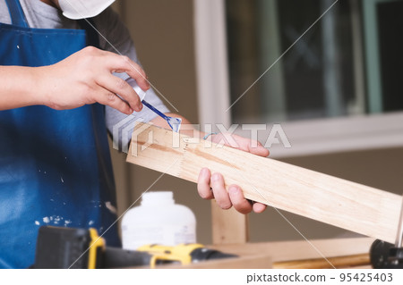 Woodworking operators are using glue to put together the wood parts to assemble and build a wooden table for their customers. Woodworking operators are using glue to put together the wood parts to assemble and build a wooden table for their customers. 95425403
