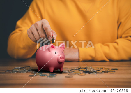 Man putting coin into piggy bank for saving money concept, business finance and investment. 95426218