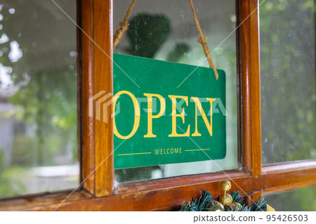 The sign was opened on the wooden door in front of the cafe. The sign was opened on the wooden door in front of the cafe. 95426503