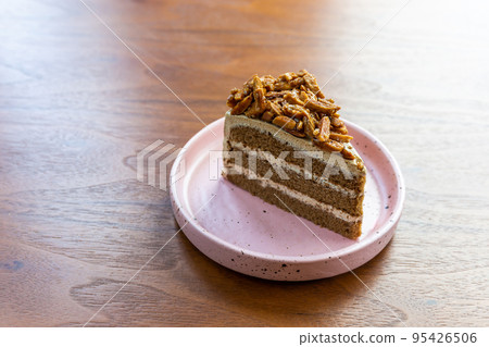 Chocolate cake with nuts in white polka dot tiled dish on wooden table. Chocolate cake with nuts in white polka dot tiled dish on wooden table. 95426506