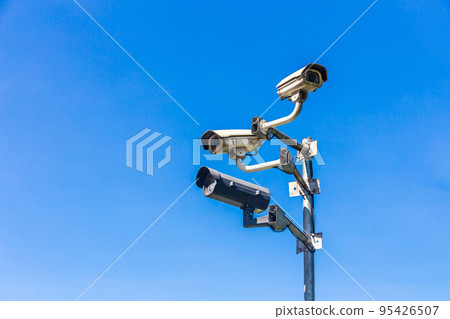 Old security camera or CCTV sits on a pole with a sky background. Old security camera or CCTV sits on a pole with a sky background. 95426507