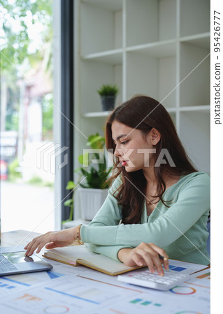 Female entrepreneurs, accountants, half girl employees use the computer and calculator to calculate financial documents to check your taxes and plan your investment budget Female entrepreneurs, accountants, half girl employees use the computer and calculator to calculate financial documents to check your taxes and plan your investment budget 95426777