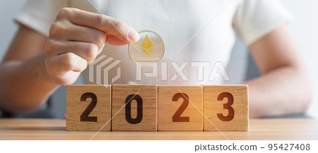 hand holding silver Ethereum or ETH cryptocurrency over 2023 Year blocks. Crypto trading, is Digital Money, blockchain and New Year concepts 95427408