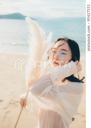 Photo of a woman standing by the beach Photo of a woman standing by the beach 95427551