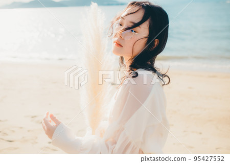 Photo of a woman standing by the beach Photo of a woman standing by the beach 95427552