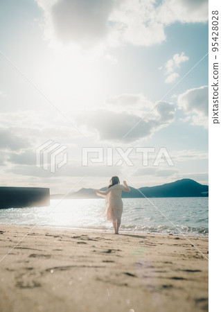 Photo of a woman standing by the beach 95428028