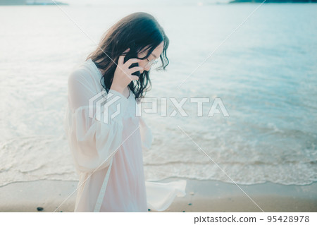 一個女人在沙灘上打電話的照片 一個女人在沙灘上打電話的照片 95428978