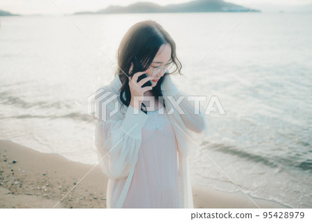 一個女人在沙灘上打電話的照片 一個女人在沙灘上打電話的照片 95428979
