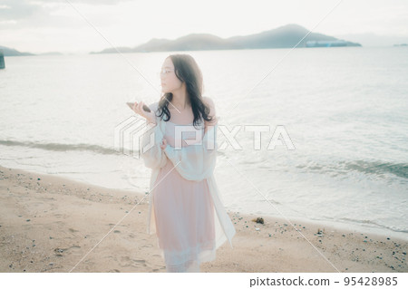 一個女人在沙灘上打電話的照片 95428985