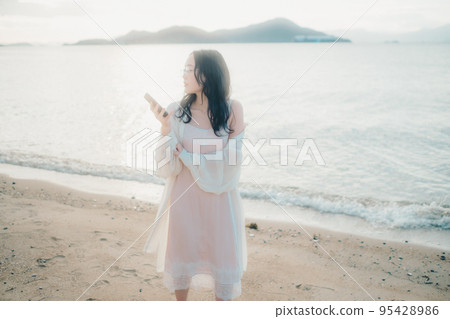 一個女人在沙灘上打電話的照片 95428986