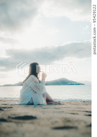 一個女人在沙灘上打電話的照片 95429122