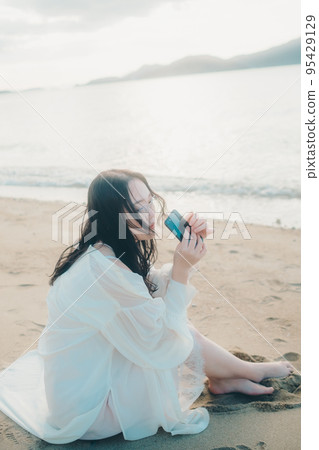 Photo of a woman making a phone call on the beach Photo of a woman making a phone call on the beach 95429129
