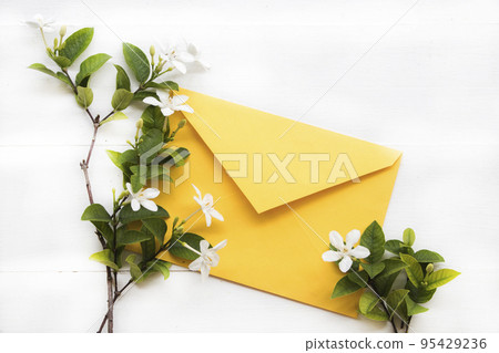 white flowers jasmine with yellow envelope arrangement flat lay postcard style 95429236