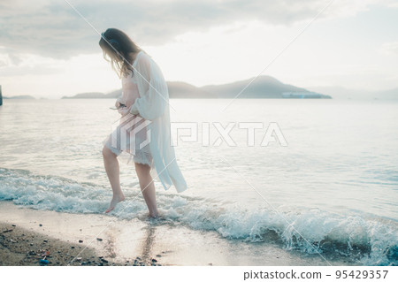 一個女人在沙灘上聽音樂的照片 一個女人在沙灘上聽音樂的照片 95429357