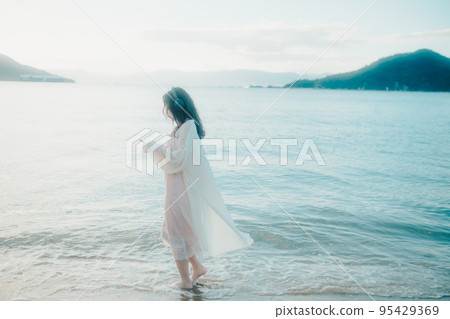 一個女人在沙灘上聽音樂的照片 一個女人在沙灘上聽音樂的照片 95429369