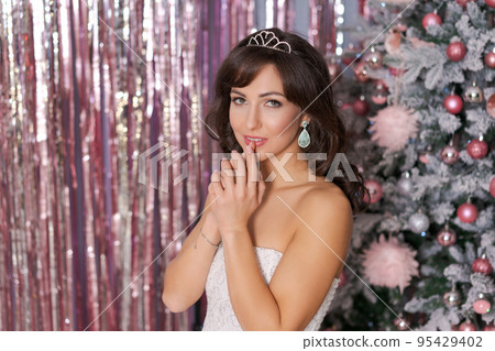 Beautiful caucasian woman decorates christmas tree indoors. Christmas Beautiful caucasian woman decorates christmas tree indoors. Christmas 95429402