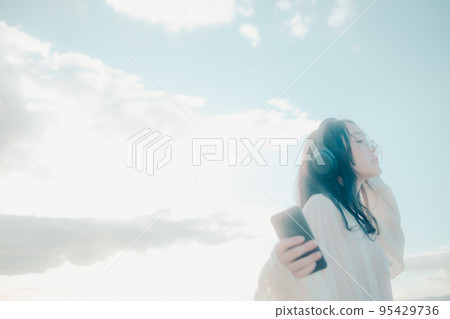Photo of a woman listening to music on the beach 95429736