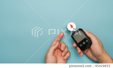 Man with red blood drop and glucose meter over blue background. Medicine, diabetes and health care concept 95429855