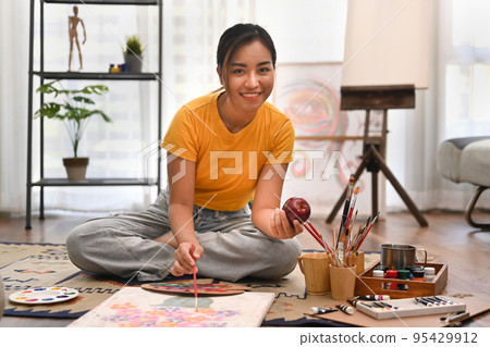 Creative woman painting picture on canvas, sitting in bright are workshop. Leisure activity, creative hobby and art concept Creative woman painting picture on canvas, sitting in bright are workshop. Leisure activity, creative hobby and art concept 95429912