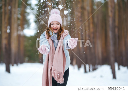 Cute young woman is playing with snow in the forest. Winter lifestyle happiness emotions nature. 95430041