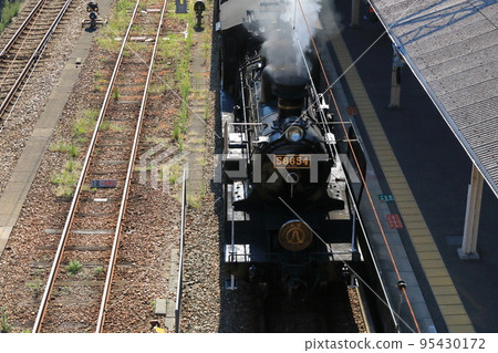 A view of the steam locomotive arriving at Tosu Station, the final stop, blowing smoke vigorously. 95430172