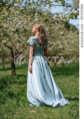 Portrait of a blonde in the park. Beautiful woman with long blond hair in a blue dress. 95430460