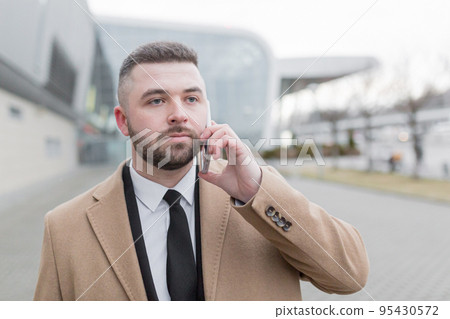 young handsome businessman goes to the airport with a suitcase talks on the phone, smiles, calls a taxi, looking for. waiting for a meeting 95430572
