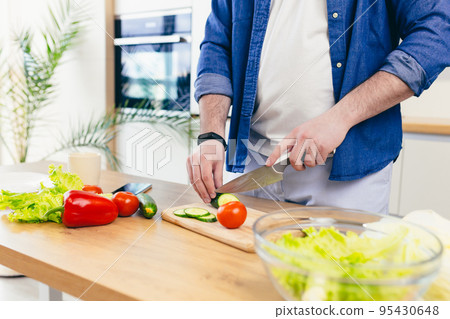 Close-up, hands of young man preparing at home in the kitchen fresh vegetables and fruits, healthy food 95430648
