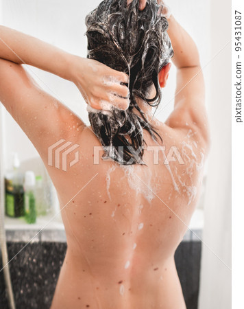 Naked woman with long hair takes a shower. Woman washes her hair with shampoo. Morning routine in modern urban apartment. White bathroom. 95431087