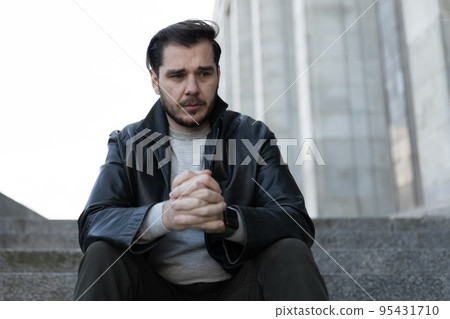 portrait of a man sitting on the steps in emotional distress with guilt on his face portrait of a man sitting on the steps in emotional distress with guilt on his face 95431710