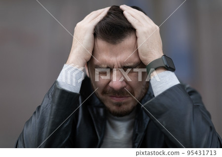 emotional portrait of a man suffering from migraine covers his head with his hands 95431713
