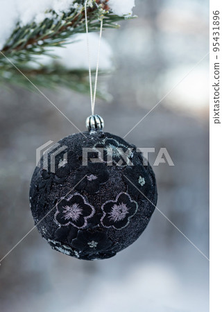 Hanging black glitter Christmas ball on spruce and over blurred background 95431896