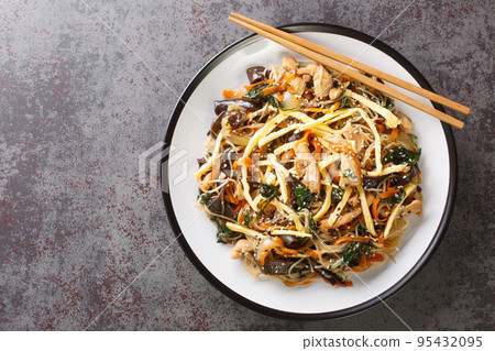 Korean food stir-fried with noodles, meat, mushrooms and vegetables called Japchae closeup on the plate. Horizontal top view Korean food stir-fried with noodles, meat, mushrooms and vegetables called Japchae closeup on the plate. Horizontal top view 95432095