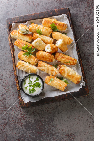 Sigara Boregi Turkish Cigar Shaped Rolls stuffed with cheese and herbs closeup on the wooden board. Vertical top view 95432108