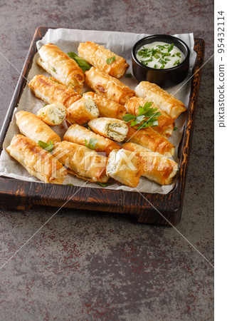sigara boregi is a famous Turkish deep-fried pastry crispy rolls of thin dough are stuffed with a creamy mixture of cheese and parsley closeup on the wooden board. Vertical sigara boregi is a famous Turkish deep-fried pastry crispy rolls of thin dough are stuffed with a creamy mixture of cheese and parsley closeup on the wooden board. Vertical 95432114