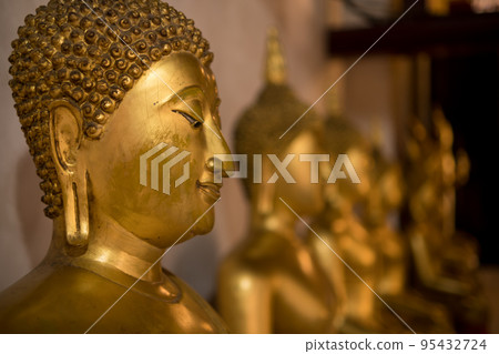 Close-up shot face of golden buddha statue sit in row at buddhist hall and focus in front of the image and blur background. Close-up shot face of golden buddha statue sit in row at buddhist hall and focus in front of the image and blur background. 95432724