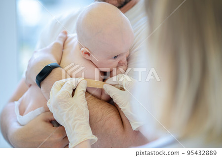 Pediatrician carrying out a medical procedure on the neonate 95432889