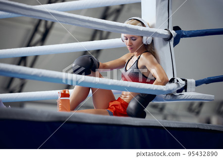 Young female athlete, professional boxer, kickboxer have a rest after hard training at sports gym. Concept of sport, workout, active and healthy lifestyle 95432890