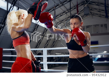 Two female professional boxers boxing at boxing ring at sport gym. Two muscular athletes in boxing gloves sparring. Sport, workout, strength 95432912